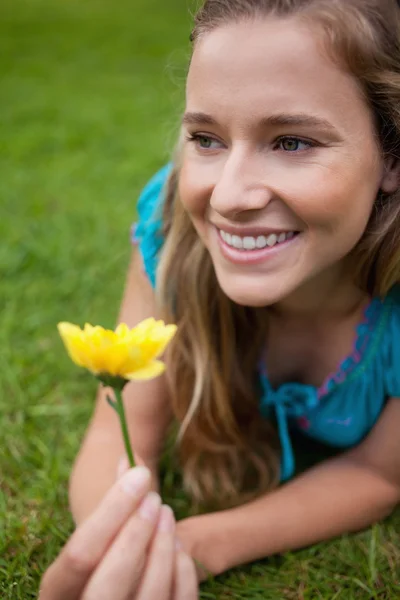 Молодая улыбающаяся девушка смотрит в сторону, лежа на траве и холе — стоковое фото
