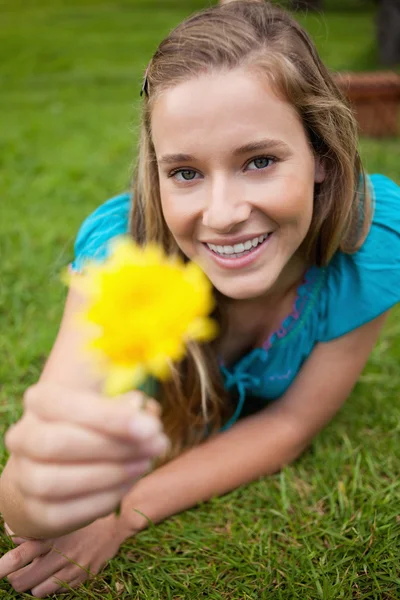 Sorrindo jovem segurando uma flor amarela enquanto olha para o — Fotografia de Stock
