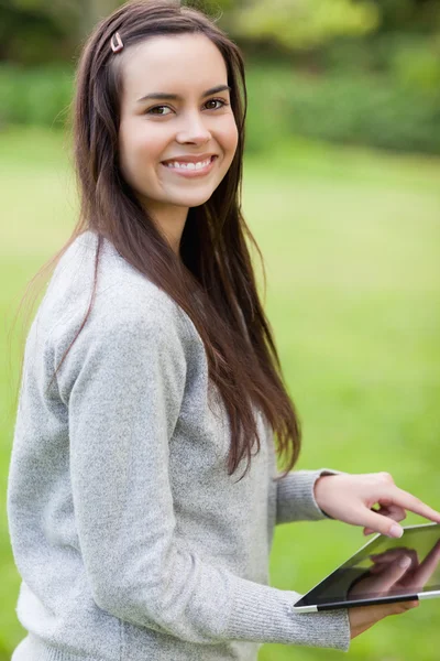 Young smiling woman using her tablet pc while looking at the cam — Stock Photo, Image
