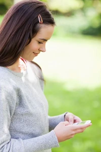 Entspannte junge Frau schickt einen Text, während sie im Land steht — Stockfoto