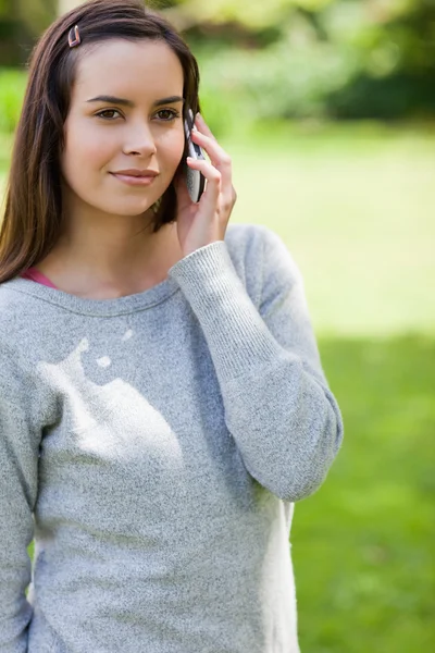 Joven mujer seria llamando con su teléfono celular mientras está de pie en — Foto de Stock