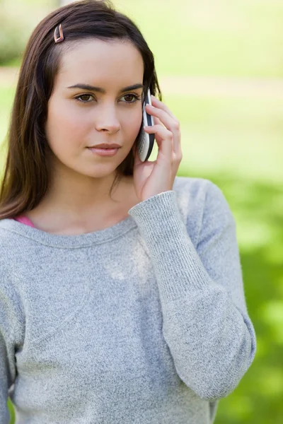 Серьёзная молодая женщина пользуется телефоном, стоя в кооперативе. — стоковое фото
