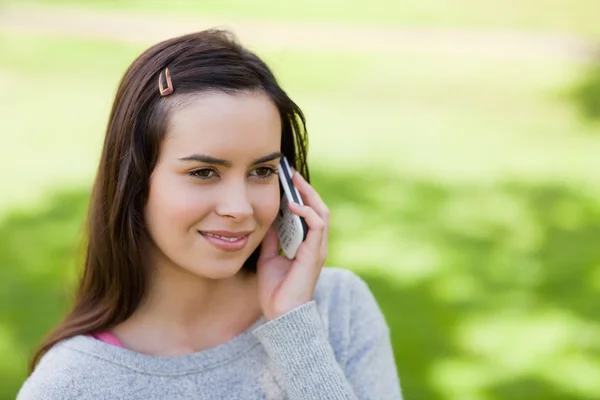 Young relaxed girl talking on the phone while standing in the co — Stock Photo, Image