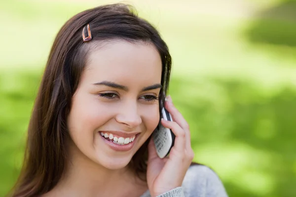 Uśmiechnięta młoda kobieta za pomocą jej telefon komórkowy na wsi — Zdjęcie stockowe