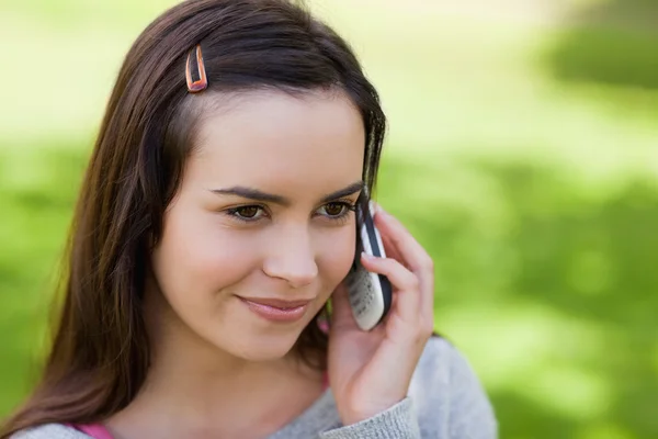Молодая расслабленная девушка разговаривает по телефону в парке — стоковое фото