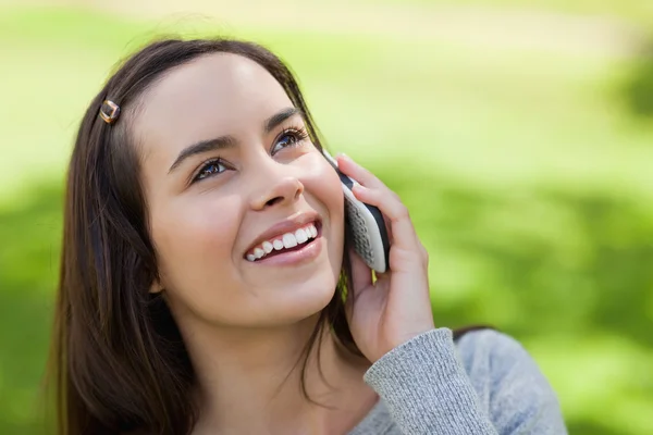 Молодая улыбающаяся женщина смотрит вверх во время разговора по телефону — стоковое фото
