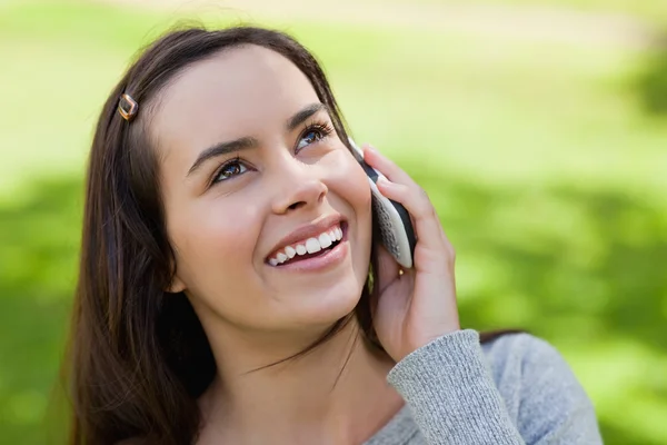 Молодая улыбающаяся женщина разговаривает по телефону, глядя вверх — стоковое фото