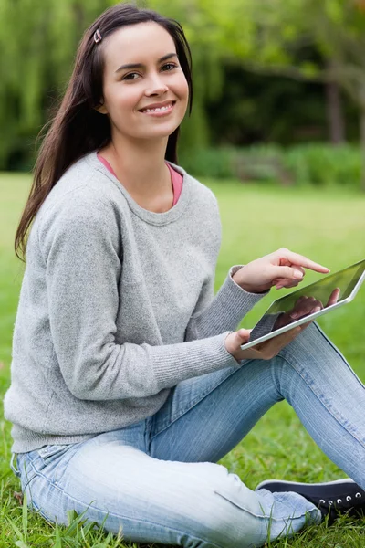 Jonge lachende vrouw kijken naar de camera terwijl haar tabl — Stockfoto