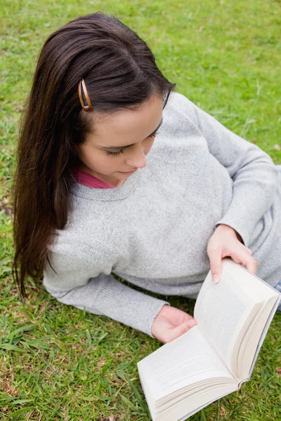 Ung kvinna läser en bok liggande i gräset — Stockfoto