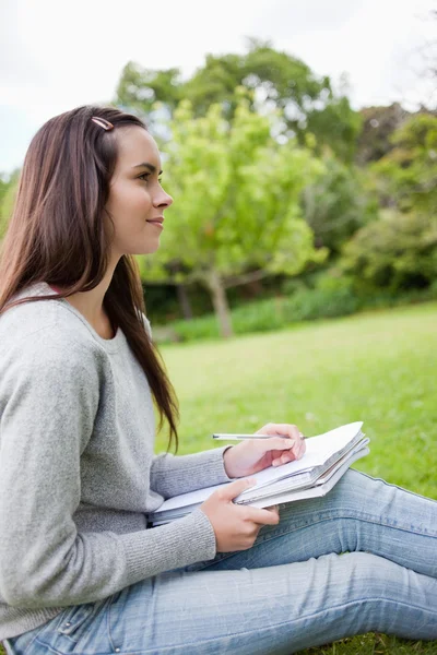 Young relaxed girl looking far away while holding her pen and he — Stock Photo, Image