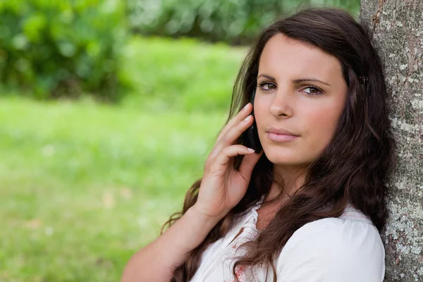 Jovem mulher séria chamando com seu telefone celular enquanto sentado — Fotografia de Stock