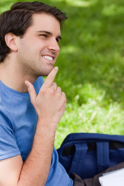 Молодой улыбающийся мужчина кладет палец на подбородок — стоковое фото
