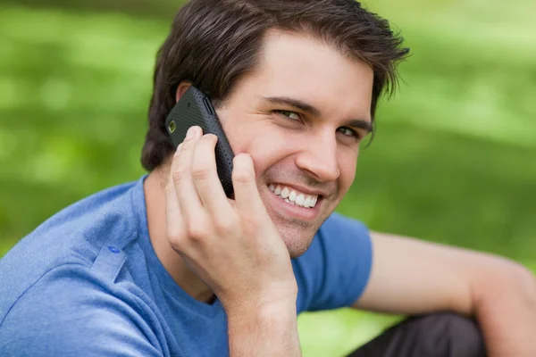 Smiling young man looking straight at the camera while talking o — Stock Photo, Image