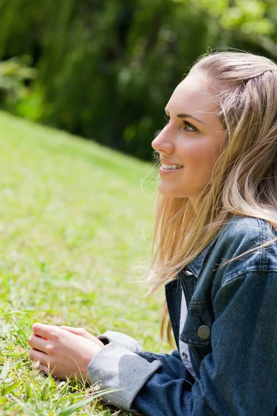 Giovane ragazza sorridente sdraiata sull'erba in campagna — Foto Stock