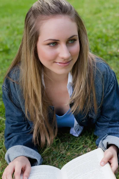 Young smiling girl looking towards the side while lying on the g — Stock Photo, Image