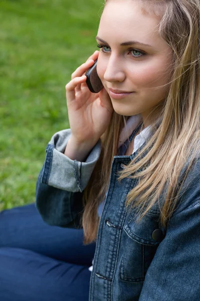 Młoda blond kobieta wywołanie z jej telefon komórkowy siedząc i — Zdjęcie stockowe