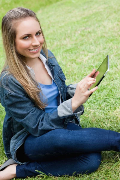Young happy girl looking at the camera while using her tablet co — Stock Photo, Image