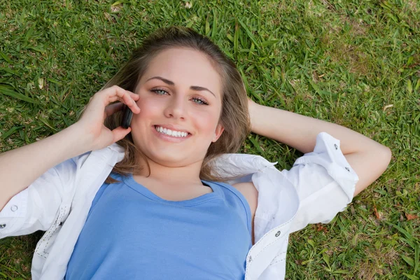 Unga leende blonda flickan liggande på rygg medan du tittar — Stockfoto