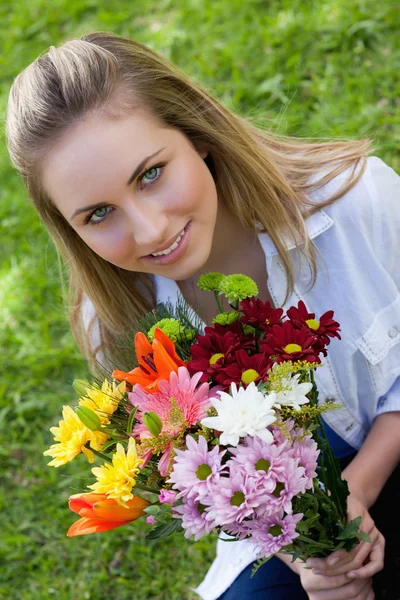 Adolescente loira atraente segurando um belo monte de flor — Fotografia de Stock