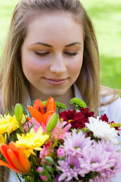Junge friedliche Frau riecht einen Blumenstrauß, während sie h schließt — Stockfoto