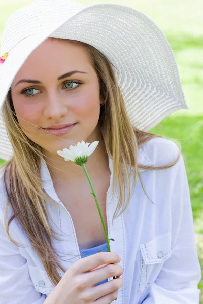 Joven chica pacífica sosteniendo una flor blanca en un parque — Foto de Stock