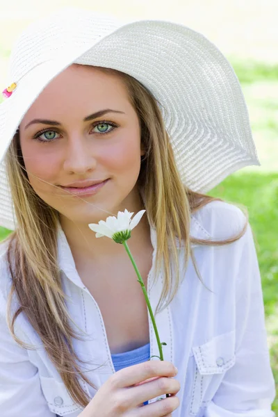 Menina loira jovem usando um chapéu branco enquanto segurando um fluxo branco — Fotografia de Stock