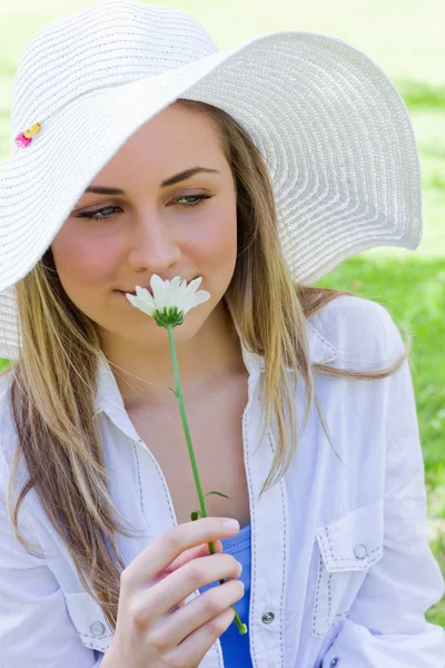 Young peaceful blonde girl smelling a white flower while standin — Stock Photo, Image