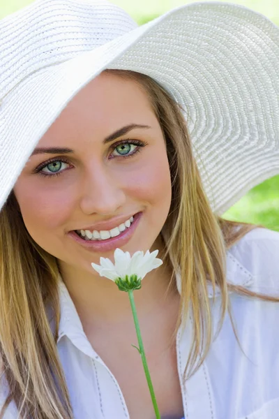 Jovem menina loira atraente usando um chapéu branco enquanto segurando um — Fotografia de Stock