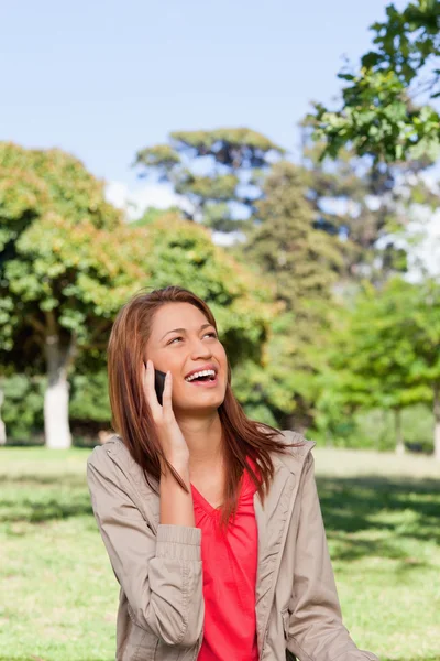 Frau lacht am Telefon, während sie in die Sonne schaut — Stockfoto