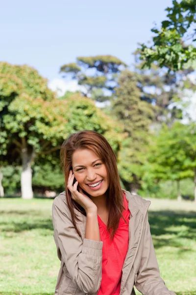 Mujer joven sonriendo mientras mira a la cámara en un gr brillante — Foto de Stock