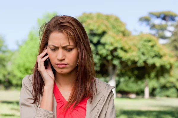 Woman looking towards the ground while on the phone in a bright — Stock Photo, Image