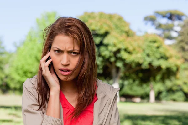 Žena s vážným výrazem mluví po telefonu ve světlé — Stock fotografie