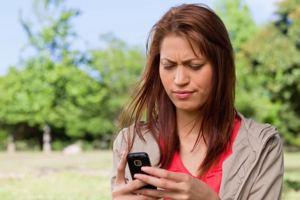 Young woman with a concerned expression reading a text message — Stock Photo, Image