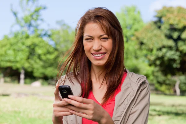 Giovane donna sorridente felicemente mentre tiene in mano un telefono — Foto Stock