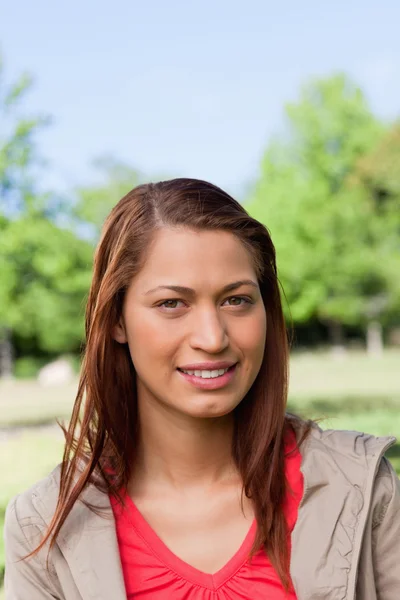 Frau lächelt, als sie direkt vor ihr in einem Park steht — Stockfoto