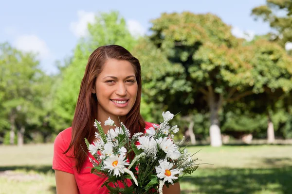Femme regardant au loin et tenant un bouquet de fleurs — Photo