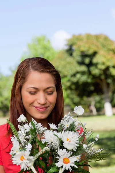 Молодая женщина осматривает букет цветов, стоя в одном ряду — стоковое фото