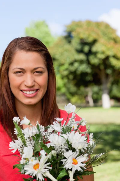 Junge Frau blickt in die Ferne, während Blumen in einem Park blühen — Stockfoto