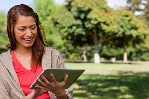 Young woman smiling enthusiastically while using a tablet — Stock Photo, Image