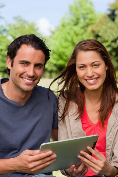 Man and a woman look ahead while holding a tablet — Stock Photo, Image