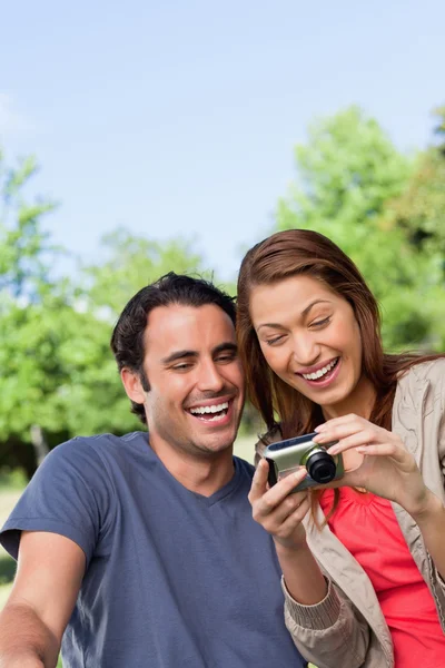 Two friends smiling happily as the look at the photo collection — Stock Photo, Image