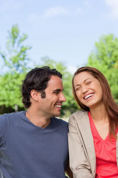 Homem olhando seu amigo como ela está rindo alegremente enquanto sentado — Fotografia de Stock
