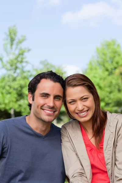 Two friends smiling as the look ahead while leaning against each — Stock Photo, Image