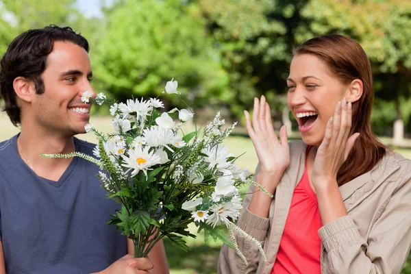 Mulher rindo excitadamente como ela é apresentada com flores por ela — Fotografia de Stock