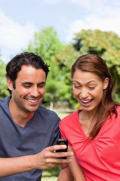 Woman watches as she is shown something on the friend's phone — Stock Photo, Image