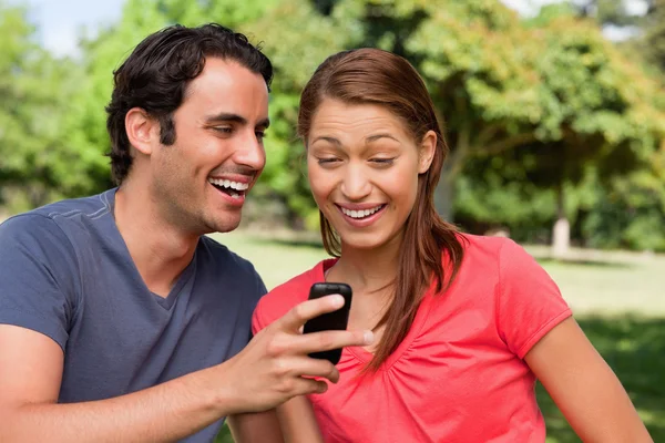 Hombre riendo mientras muestra algo en su teléfono a su amigo — Foto de Stock