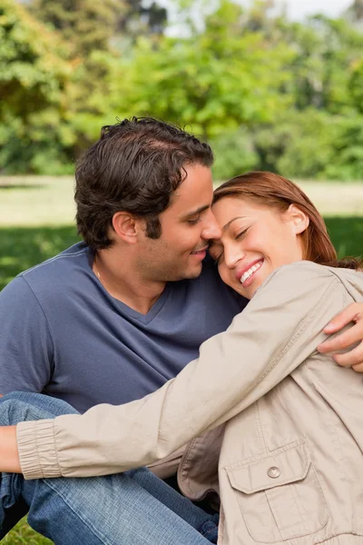 Mann lächelt, als seine Freundin ihren Kopf auf seine Schultern legt — Stockfoto