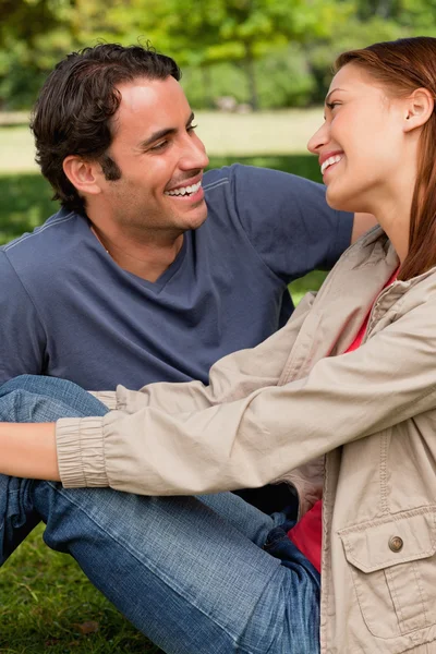 Two friends laughing while they are both sitting on the grass — Stock Photo, Image