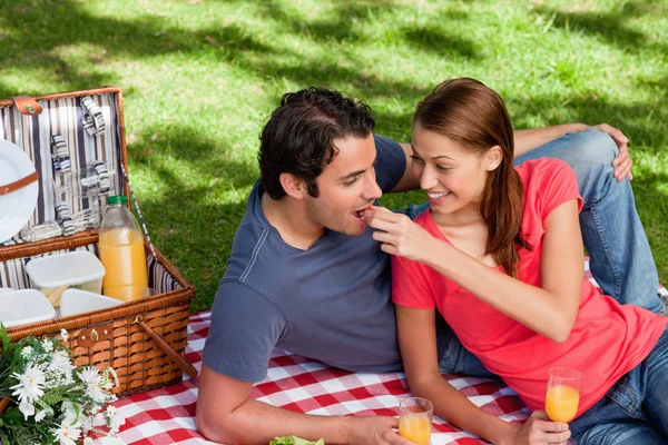 Young woman feeding her friend as they as they lie on a blanket — Stock Photo, Image