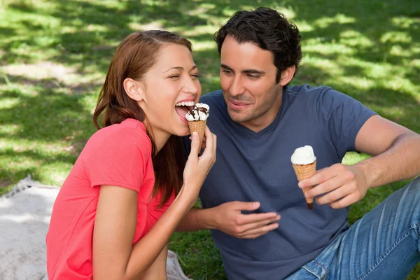 Mujer comiendo helado mientras se sienta con su amigo — Foto de Stock